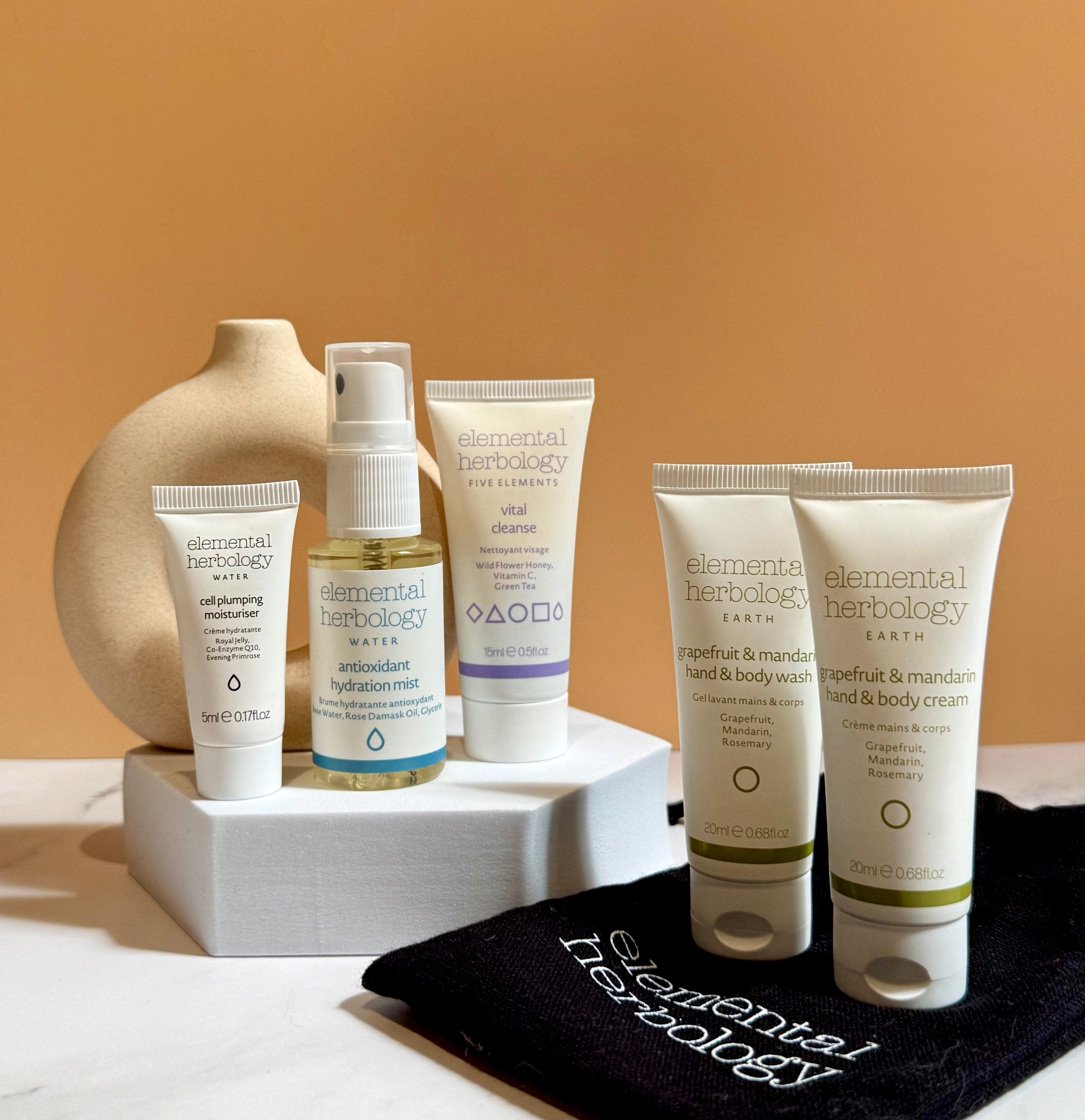 Elemental Herbology skincare products on a white surface with a beige background